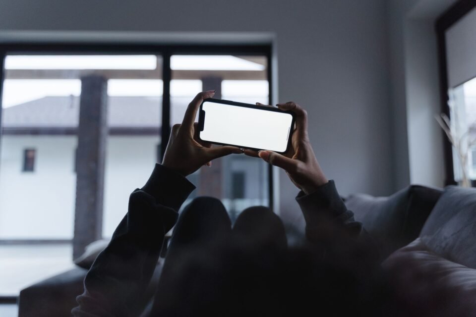 Seseorang memegang ponsel dengan layar kosong saat bersantai di sofa