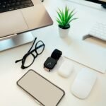 Smartphone bersama smartwatch, earbud, mouse, laptop, dan aksesori teknologi lain di atas meja putih