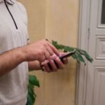 Seseorang menggunakan smartphone dengan satu tangan di dalam ruangan
