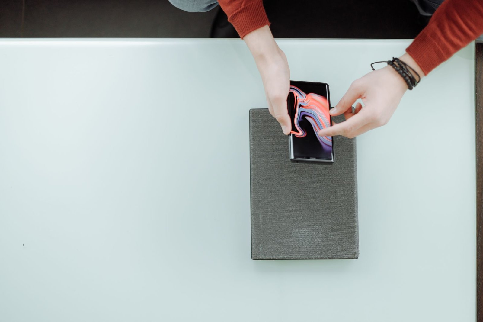 Seseorang memeriksa smartphone di atas meja dengan kedua tangan