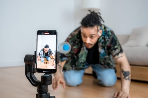 Seorang pria merekam video di dalam ruangan menggunakan ponsel yang terpasang pada gimbal.