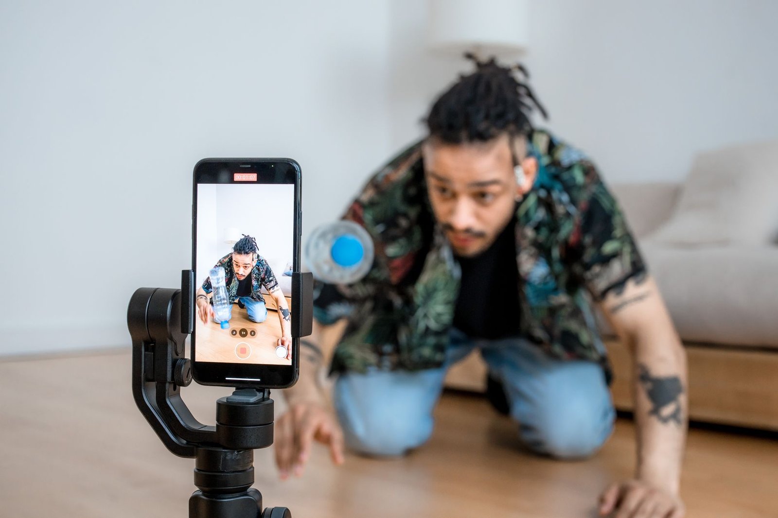 Seorang pria merekam video di dalam ruangan menggunakan ponsel yang terpasang pada gimbal.