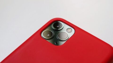 Close-up tiga lensa kamera iPhone pada bagian belakang ponsel dengan casing merah.