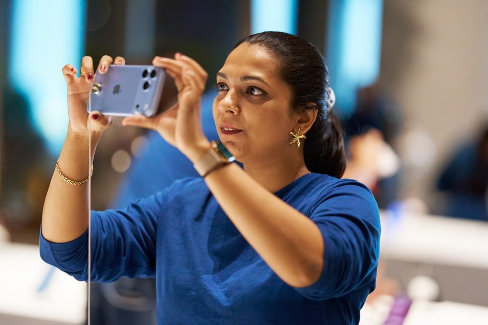 Seorang pelanggan memegang iPhone 18 Pro secara horizontal di dalam Apple Store.