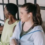 Dua orang duduk di dalam ruangan sambil menggunakan earbud nirkabel