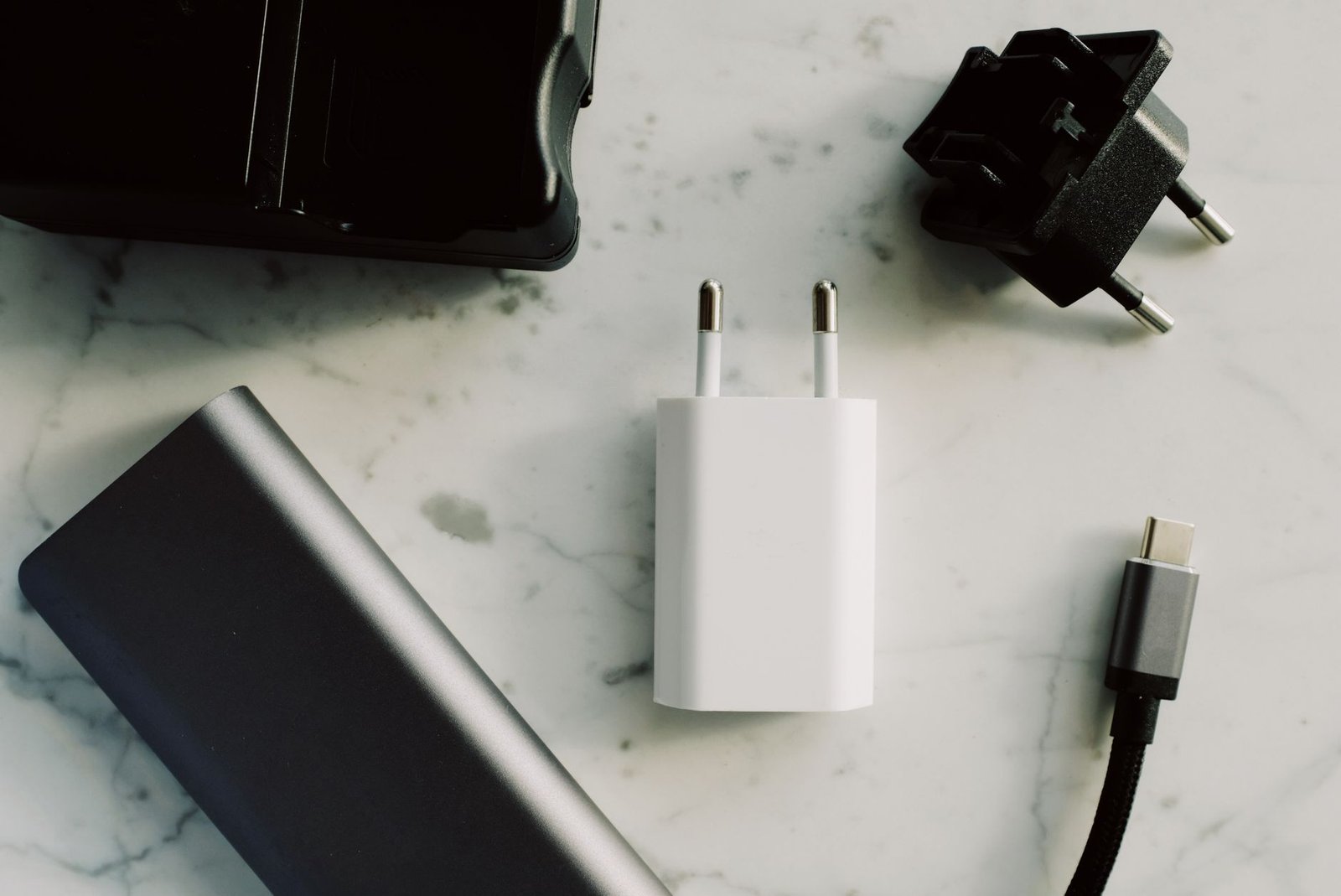 Beragam adaptor, kabel USB-C, dan power bank tersusun di atas permukaan marmer.