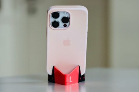 iPhone berwarna terang dalam casing terpasang pada dudukan meja.