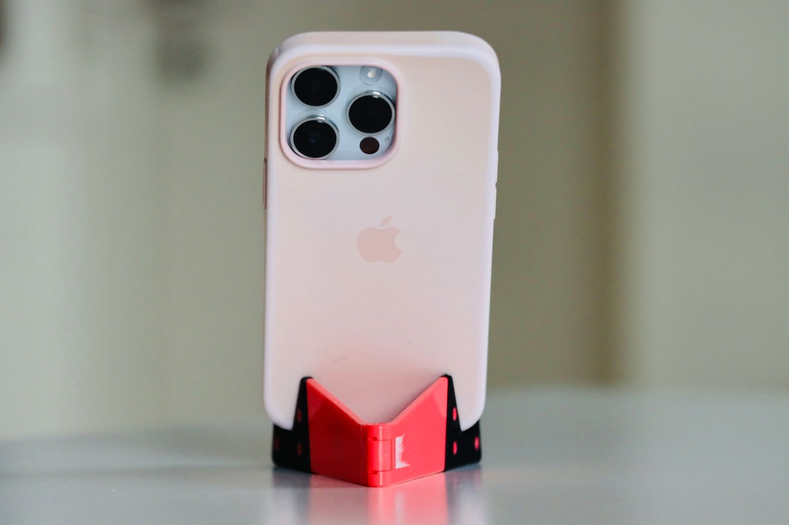 iPhone berwarna terang dalam casing terpasang pada dudukan meja.