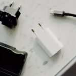 Beberapa adaptor pengisi daya, kabel USB-C, dan aksesori elektronik tersusun di atas permukaan marmer.