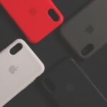 Empat casing iPhone dengan warna dan desain berbeda diletakkan di atas permukaan gelap.